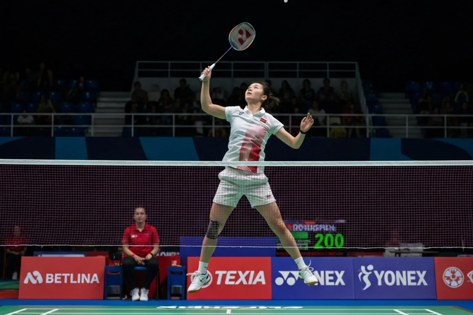 Joueuse de badminton effectuant un smash lors d’une rencontre par équipes féminine de type Coupe Uber